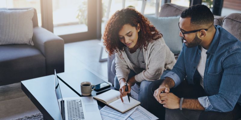 A couple sitting on a couch reviewing their budget for home purchase