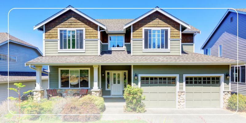Two-story suburban house with green siding, brown shingles, white trim, and a three-car garage. Perfect for an Ideal Lending home appraisal.