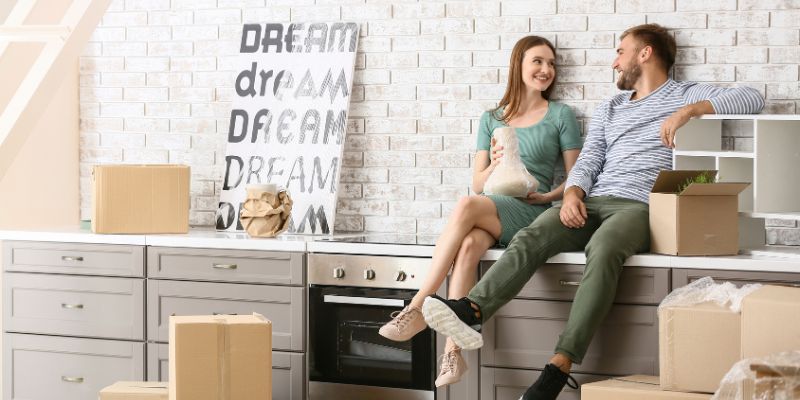 happy couple sitting on counter in new kitchen